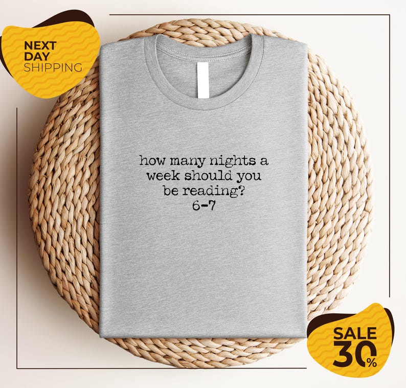 A gray t-shirt with a humorous text printed on it, placed on a woven placemat.