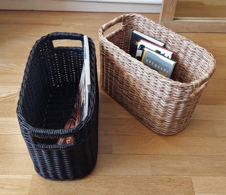 May include: Two woven magazine holders, one black and one brown, with a stack of books in the brown holder.