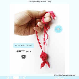 May include: A crochet pattern for a mermaid tail pouch necklace. The pattern is labeled as easy and requires medium weight yarn. The image shows a red crochet mermaid tail pouch necklace.
