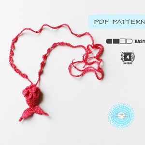 May include: A pink crocheted mermaid tail necklace with a PDF pattern for crocheting. The pattern is rated easy and uses medium weight yarn.