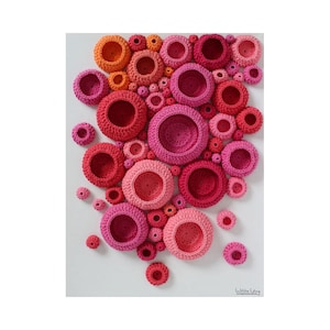 May include: A wall art piece made of crocheted circles in various shades of pink and orange. The circles are arranged in a random pattern, creating a visually appealing and textured design.