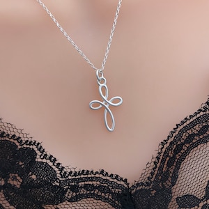 May include: A silver chain necklace with a delicate, twisted cross pendant.