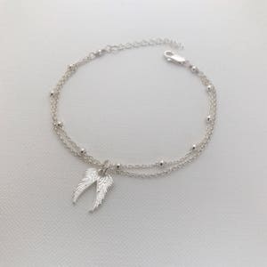 May include: A silver chain bracelet with two strands and a small angel wing charm.