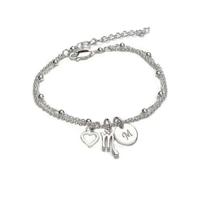 May include: Silver bracelet with a heart, a Scorpio zodiac sign charm, and a personalized initial charm. The initial charm is engraved with the letter "M".