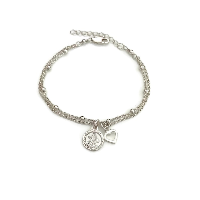 May include: A silver bracelet with two chains, a small heart charm, and a round charm with a detailed design.