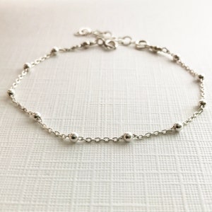 May include: A delicate silver chain anklet with small round beads.