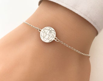 May include: A silver chain bracelet with a round charm featuring an engraved world map.