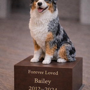 May include: A detailed sculpture of a dog, predominantly blue merle, white, and tan, sitting atop a brown rectangular base. The base is inscribed with "Forever Loved Bailey 2012-2024". The dog has blue eyes and a happy expression.