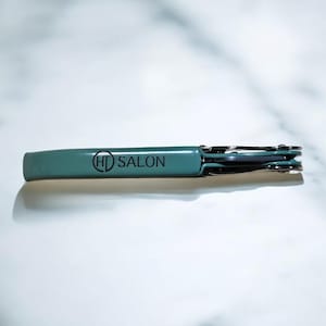 May include: A teal blue metal bottle opener with the text "HD SALON" printed on the handle.