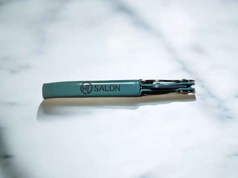 May include: A teal blue metal bottle opener with the text "HD SALON" printed on the handle.