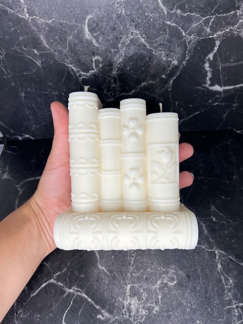 May include: A white pillar candle set with intricate floral designs. The candles are arranged in a row and have a decorative base.