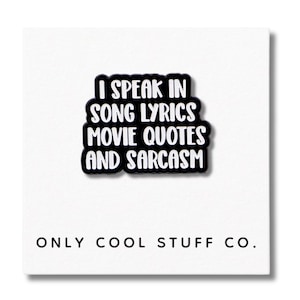 Può includere: Spilla bianca e nera con la scritta "I SPEAK IN SONG LYRICS MOVIE QUOTES AND SARCASM". La spilla è su sfondo bianco con la scritta "ONLY COOL STUFF CO." sotto.