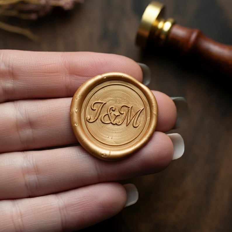 May include: Gold wax seal with the initials "J&M" embossed in a cursive font.