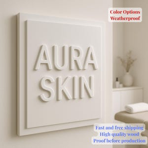 May include: A white rectangular sign with the words "AURA SKIN" in raised, white lettering. The sign is mounted on a wall. Text in the upper right corner reads "Color Options Weatherproof". Additional text at the bottom reads "Fast and free shipping High quality wood Proof before production".