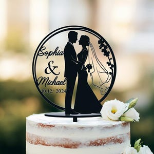 May include: Black silhouette of a bride and groom in a circle with the text "Sophia & Michael 10.12.2024" on a white cake topper.