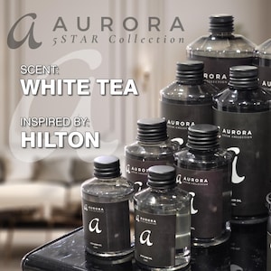 Könnte beinhalten: Eine Sammlung schwarzer Glasflaschen mit dem Text "AURORA 5STAR Collection" und "WHITE TEA" auf den Etiketten. Die Flaschen sind mit einer klaren Flüssigkeit gefüllt und haben einen schwarzen Verschluss. Der Text "INSPIRED BY: HILTON" steht ebenfalls auf dem Etikett.