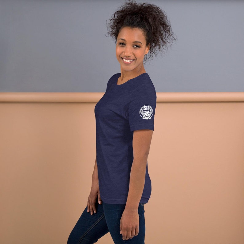May include: A navy blue t-shirt with a white graphic on the right sleeve. The graphic features a circle with the text "SEC" and a stylized image of a cross.