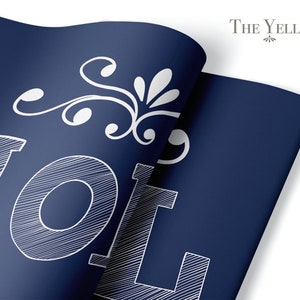 May include: A navy blue poster with white text that reads "VOL" and a white decorative flourish. The poster is folded in the upper right corner. The text "THE YELLOW DESK" is in the upper right corner.