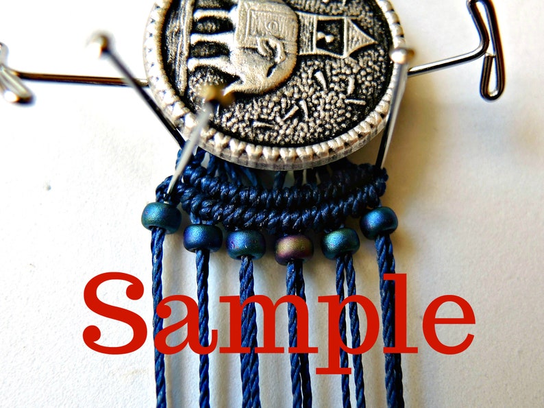 May include: A close-up of a blue and silver macrame project with a silver button featuring an elephant design. The macrame is strung with iridescent blue beads and the word "Sample" is written in red below the project.