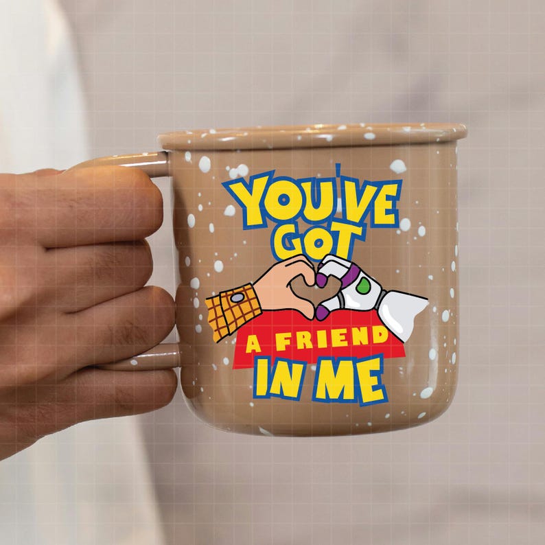 May include: Brown enamel mug with a white speckled design. The mug features a cartoon image of Woody and Buzz Lightyear from Toy Story holding hands in the shape of a heart. The text "You've Got A Friend In Me" is printed on the mug.