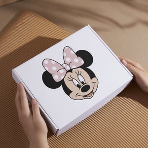 Peut inclure: Bo&icirc;te en carton blanche avec un n&oelig;ud rose &agrave; pois blancs et une image de dessin anim&eacute; de Minnie Mouse.