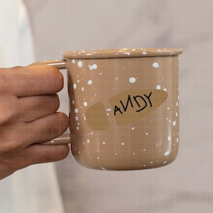 May include: A brown enamel mug with white speckles and a brown and black sticker that says "ANDY" on it.