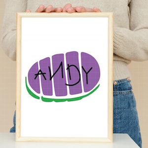 May include: A white framed print with a purple and green cartoon image of a toy story character's boot with the name "ANDY" written on it.