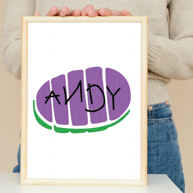 May include: A white framed print with a purple and green cartoon image of a toy story character's boot with the name "ANDY" written on it.