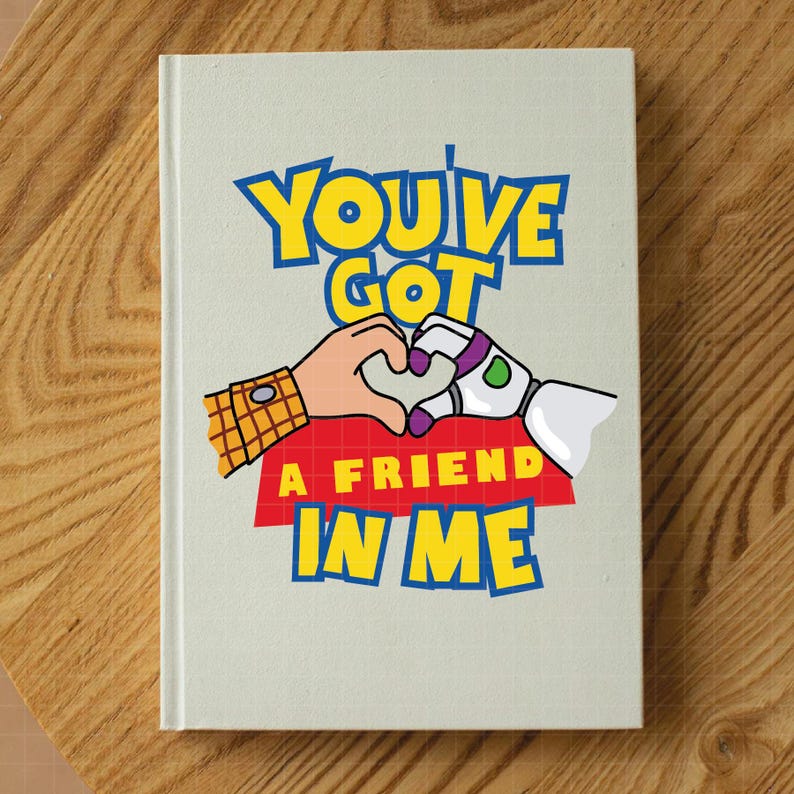 May include: A white notebook with a cartoon image of Woody and Buzz Lightyear from Toy Story. The image shows them holding hands in the shape of a heart. The text "You've Got A Friend In Me" is printed in blue, yellow, and red letters.