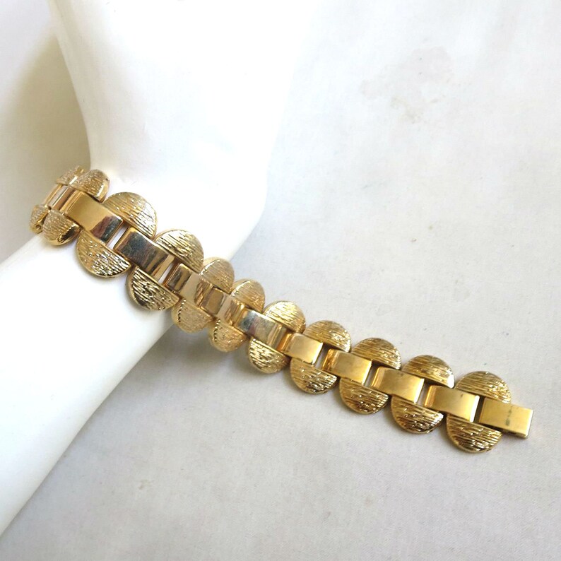 K&ouml;nnte beinhalten: Ein goldfarbenes Armband mit einem Kettenglieddesign mit runden, strukturierten Gliedern.