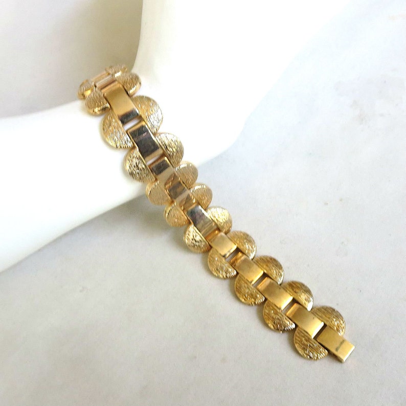 K&ouml;nnte beinhalten: Ein goldfarbenes Armband mit einem Kettenglieddesign mit runden, strukturierten Gliedern. Das Armband ist aus Metall und hat eine polierte Oberfl&auml;che.