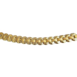 K&ouml;nnte beinhalten: Ein goldfarbenes Armband mit einem Kettenglieddesign. Jedes Glied ist eine runde, strukturierte Scheibe.