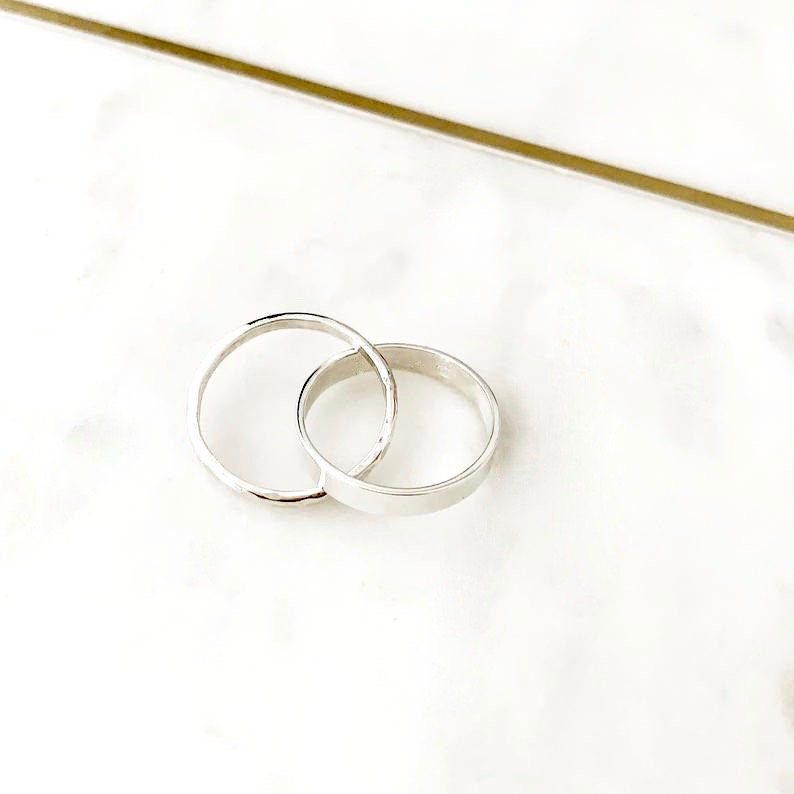 May include: Two silver rings interlocked, one with a hammered finish and the other with a smooth surface.