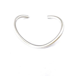 May include: A silver bangle bracelet with a curved, open design.