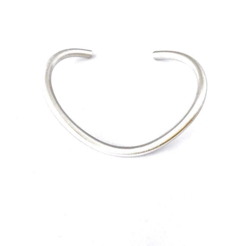 May include: A silver bangle bracelet with a curved, open design.