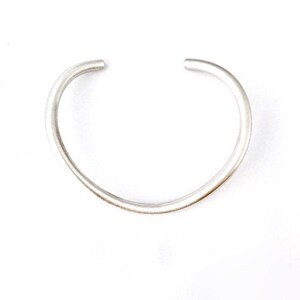 May include: A simple silver bangle bracelet with a smooth, rounded finish.