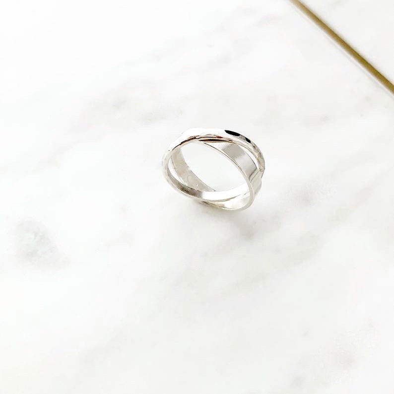 May include: A silver ring with a twisted design. The ring is made of two bands that are intertwined.