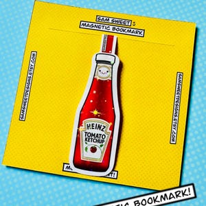 Puede incluir: Un marcapáginas magnético con un diseño de botella de ketchup Heinz roja y una cara sonriente. El marcapáginas está sobre un fondo amarillo, con el texto "SAM SWEET MAGNETIC BOOKMARK" y "MAGNETIC BOOKMARK!" impresos. También está impresa la dirección del sitio web.