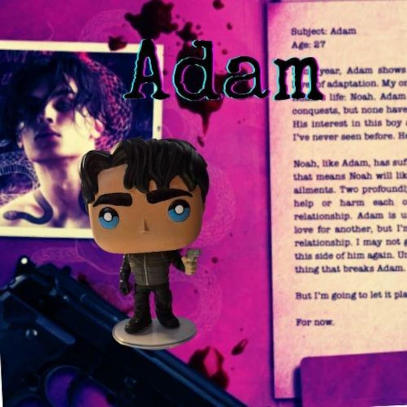 May include: A vinyl collectible figure of a character with dark hair and blue eyes, wearing a dark jacket and pants, holding a small silver object. The figure stands on a circular base against a background featuring text and a portrait.