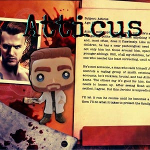 May include: A stylized vinyl figure of a man with brown hair and a beard, wearing a white lab coat over a dark shirt and pants, holding a small object. The figure is set against a background featuring a photograph of a man and printed text.