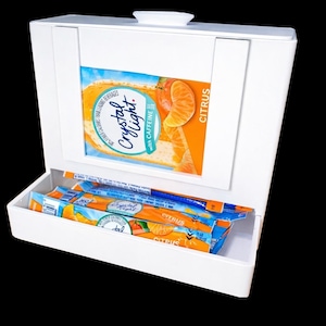 May include: White box with a hinged lid, displaying a citrus-flavored drink mix. The box has a drawer filled with individual packets of the drink mix. The packaging features oranges and the words "Crystal Light" and "Citrus".