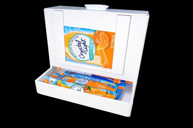 May include: White box with a hinged lid, displaying a citrus-flavored drink mix. The box has a drawer filled with individual packets of the drink mix. The packaging features oranges and the words "Crystal Light" and "Citrus".