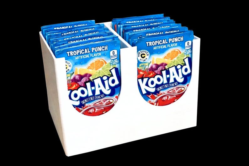 May include: A white, two-compartment organizer filled with blue packets of Kool-Aid Tropical Punch drink mix. Each packet features a colorful illustration of fruit and the Kool-Aid logo. The packets are displayed against a black background.