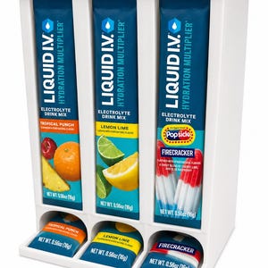 May include: A white dispenser filled with electrolyte drink mix packets. The packets are labeled "LIQUID I.V. Hydration Multiplier" and feature flavors like Tropical Punch, Lemon Lime, and Firecracker. Each packet is 0.56oz (16g).