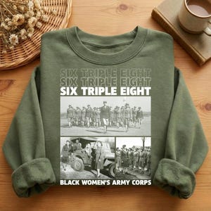 May include: Olive green sweatshirt with the text "SIX TRIPLE EIGHT" stacked three times. Below the text are three black and white images of the Black Women's Army Corps, with the text "BLACK WOMEN'S ARMY CORPS" at the bottom.