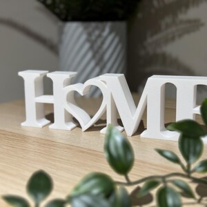 Close-up front view of 3D printed white HOME sign with heart showing crisp lettering and clean finish