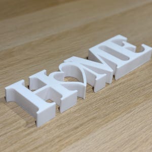 May include: White wooden letters spelling "HOME" with the "O" shaped like a heart.