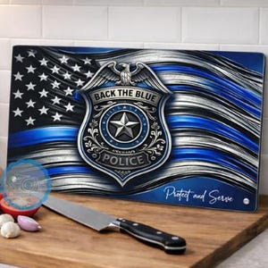 May include: A rectangular cutting board featuring a design of the American flag with a blue stripe and a police badge. The badge reads "Back the Blue" and "Police". The words "Protect and Serve" are also visible.