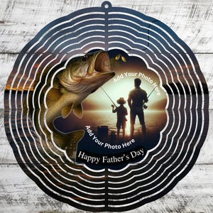 May include: A metal wind spinner with a fishing theme. The design features a large fish with an open mouth, a silhouette of a father and child fishing, and the text "Happy Father's Day". The design includes the text "Add Your Photo Here".