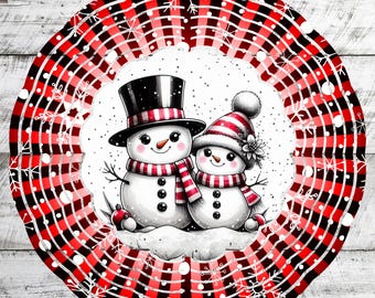 Op de afbeelding: Een rode en zwarte geruite windmolen met een witte cirkel in het midden. De cirkel toont twee sneeuwpoppen, een met een zwarte hoge hoed en de andere met een rood-witte gebreide muts. Beide sneeuwpoppen hebben zwarte ogen, een wortelneus en zwarte knopen.
